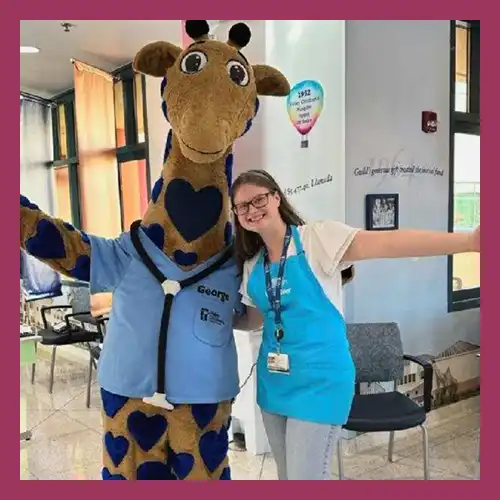 Sophia standing with a giraffe mascot