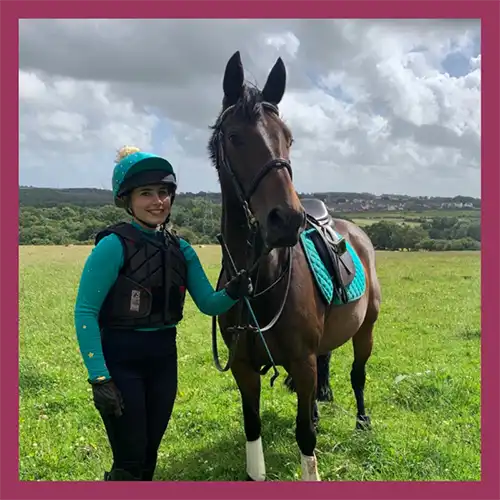 Rosie standing next to her horse wearing riding gear