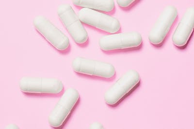 White pills on a pink background
