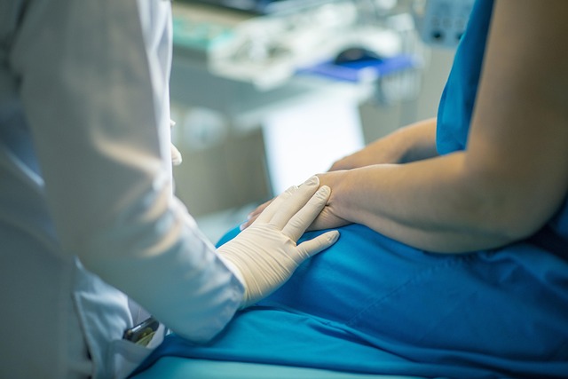 Nurse sitting next to patient and touching the patient's hand