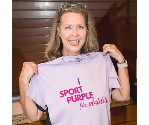 Sharon holding up a Sport Purple for Platelets T-shirt